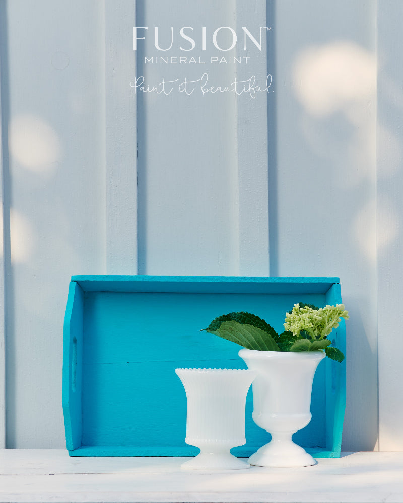 Wooden tray painted in Fusion's blue Azure with white containers and greenery against a light blue wall