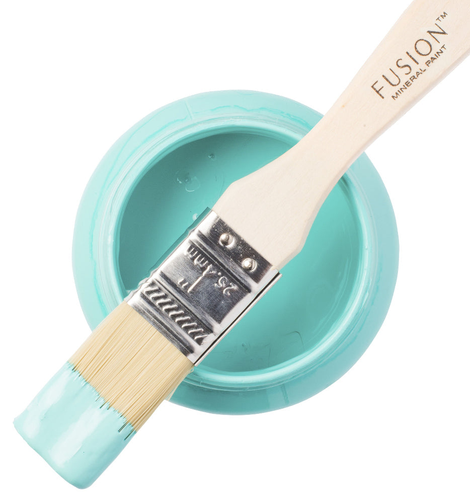 Paintbrush with turquoise handle and white bristles in a container of Azure paint, Fusion brand visible.