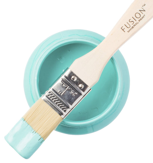 Paintbrush with turquoise handle and white bristles in a container of Azure paint, Fusion brand visible.