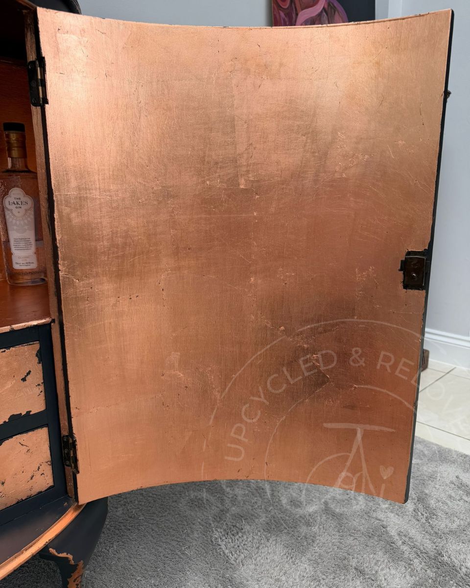 Inside of an upcycled demi lune drinks cabinet door finished in copper leaf with a base of Fusion Mineral Paint Ash, a charcoal black.