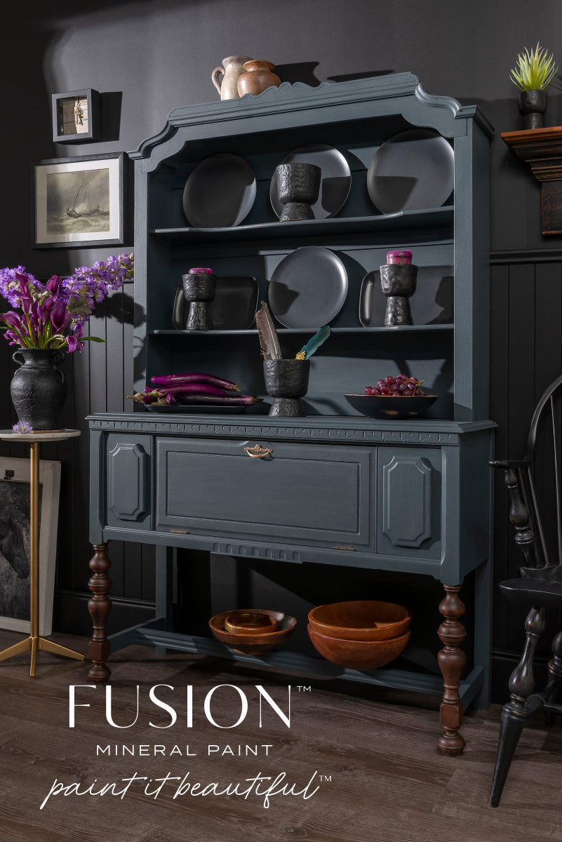 Cabinet painted in Cambridge Fusion Mineral paint, a dark grey-blue, with decorative items against a dark wall