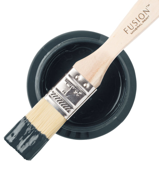 Paint brush resting on a pot of Cambridge Fusion Mineral Paint on a white background.