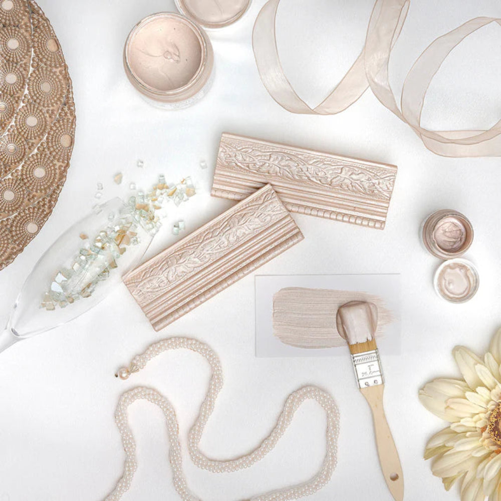 Decorative items painted in Fusion Mineral Paint Metallic Champagne including a lace doily, wooden blocks, a brush, and flowers