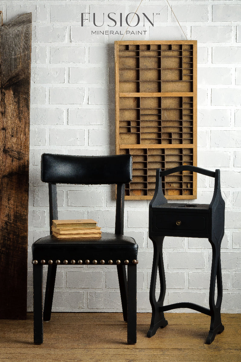 Chair and table painted in Fusion Coal Black set against a white brick wall