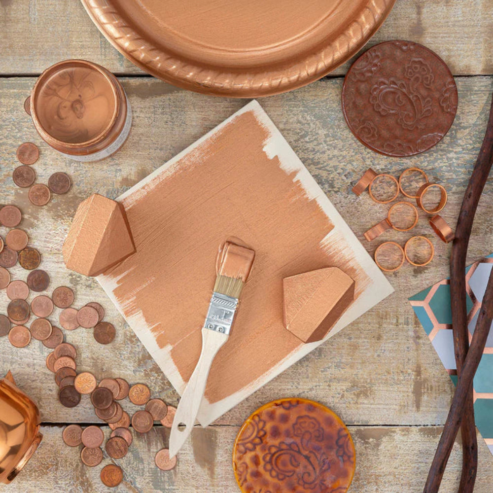 Fusion Copper Metallic painted items including plates, coins, and a paintbrush on a wooden surface.