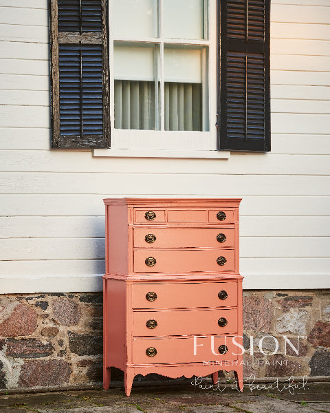 Dresser painted in Coral Fusion Mineral Paint placed against a white wall with black shutters