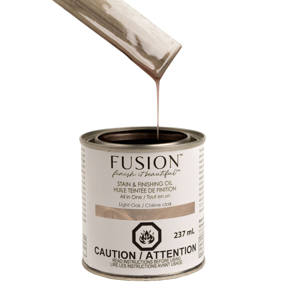 Fusion Stain and Finishing Oil in Light Oak dripping off a wooden stirrer into a tin