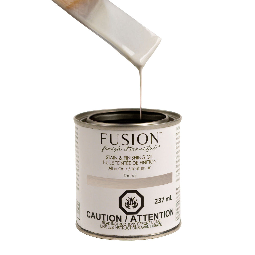 Fusion Stain and Finishing Oil in Taupe dripping off a wooden stirrer into a tin