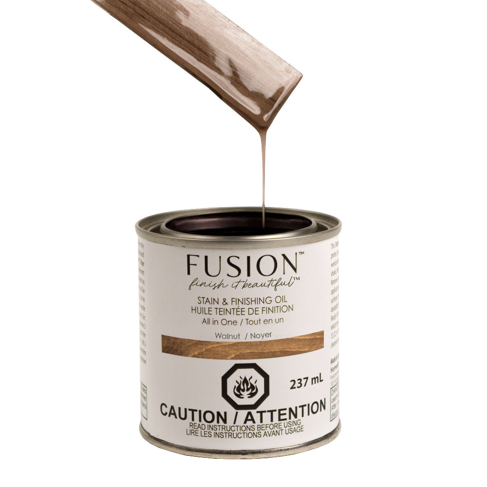 Fusion Stain and Finishing Oil in Walnut dripping off a wooden stirrer into a tin