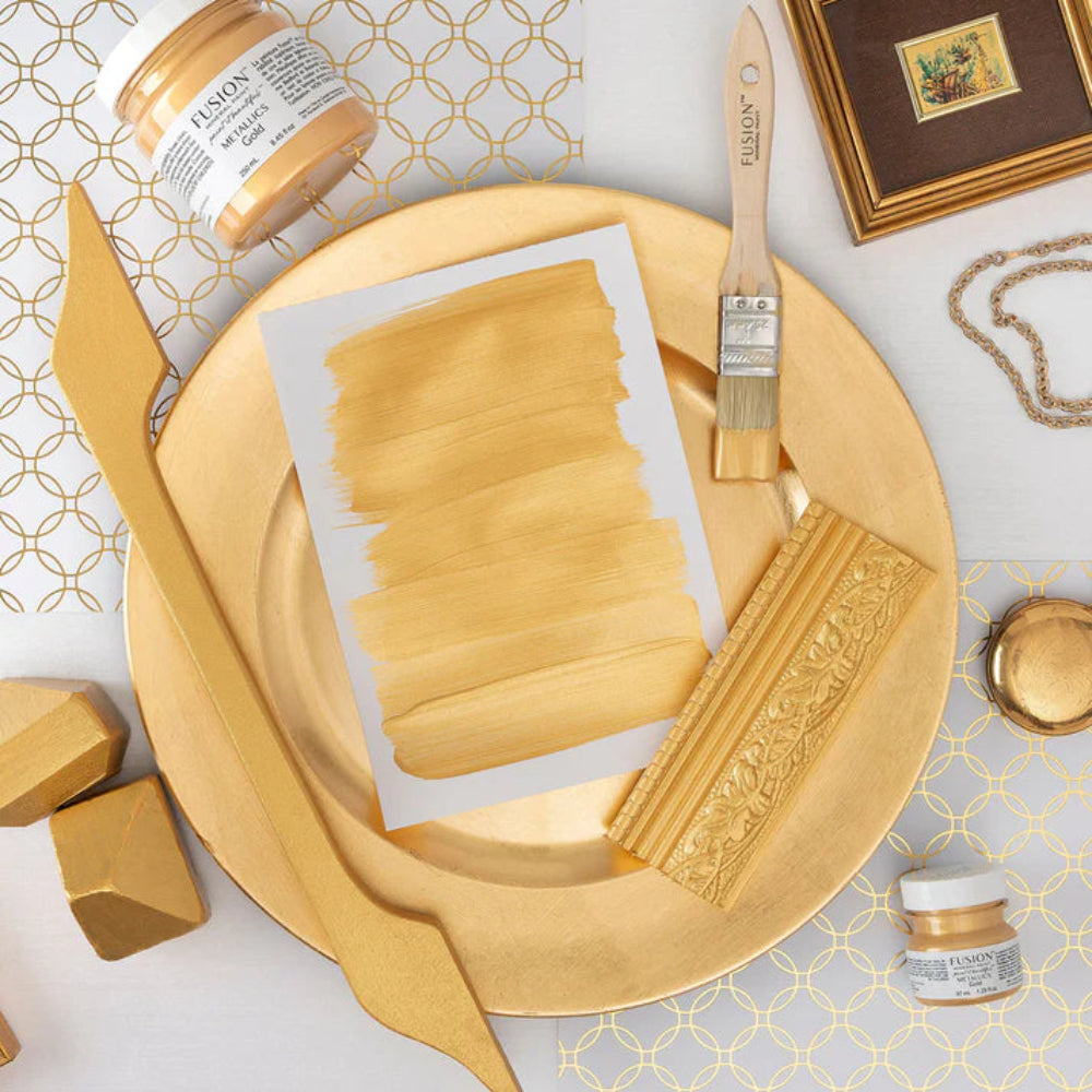 Decorative elements and paint swatches in Metallic Gold with a brush and Fusion Mineral Paint jar on a patterned surface