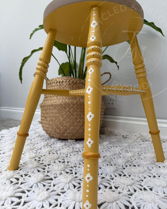 Upcycled stool with a raw pine top and legs painted in Fusion Mineral Paint in Prairie Sunset, a mustard yellow, finished with hand-painted folk-inspired decorative patterns in white.