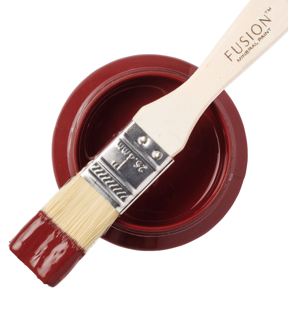 Paint brush with red Highlander paint from the Fusion Mineral Pain range sat atop a container on a white background