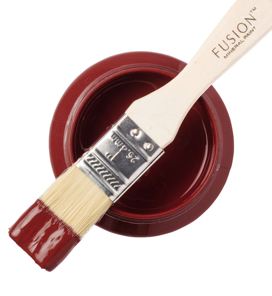 Paint brush with red Highlander paint from the Fusion Mineral Pain range sat atop a container on a white background