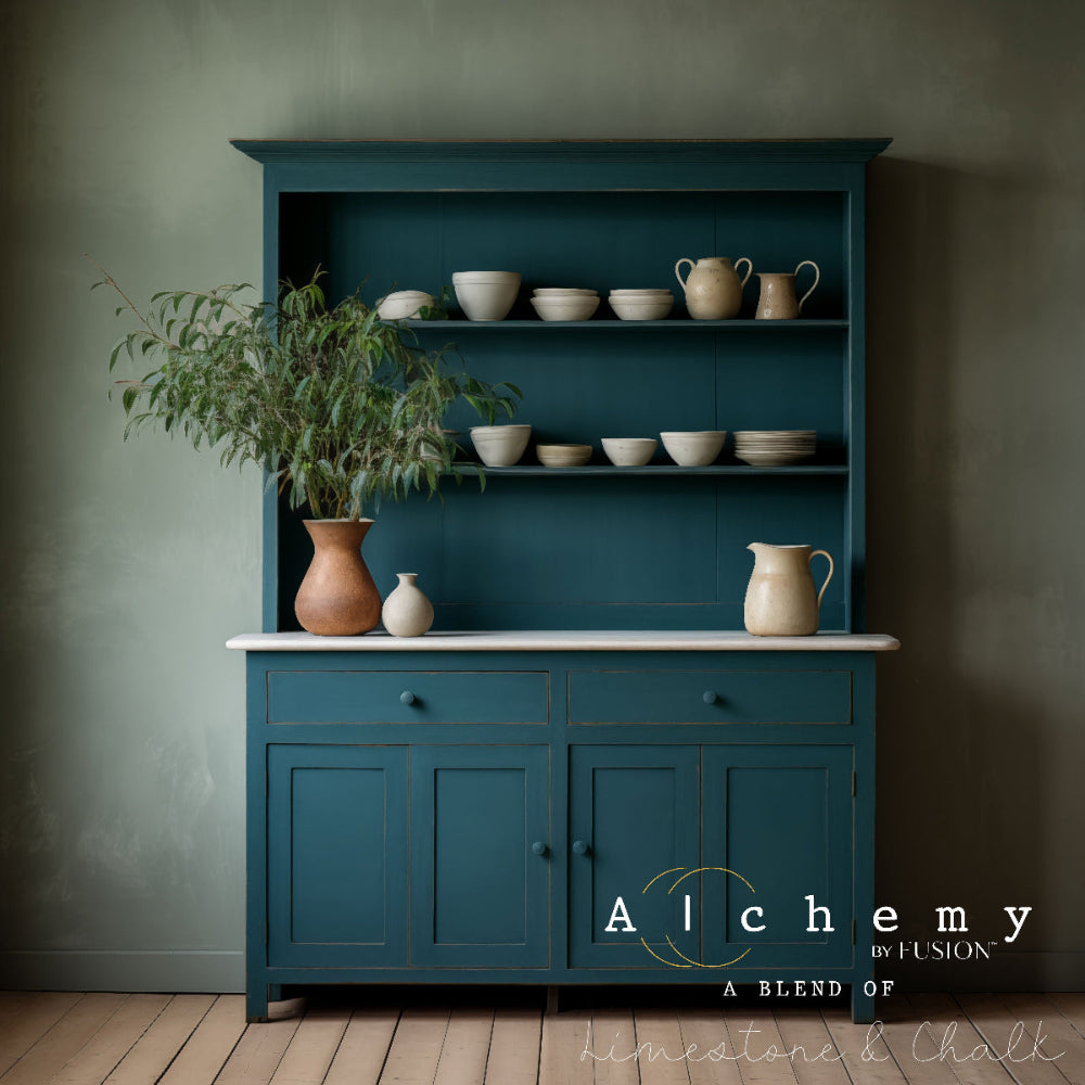 Dresser painted in blue-green Lagoon Alchemy paint with ceramic items and a plant against a dark wall