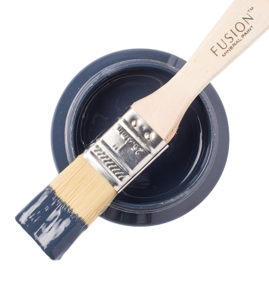 Paint brush with Midnight Blue paint from the Fusion Mineral Paint range sat atop a container on a white background