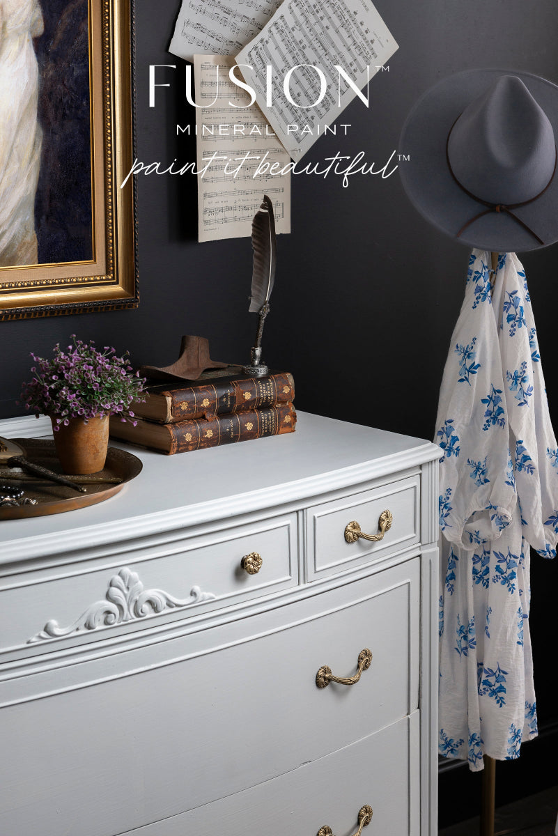 White dresser painted in Fusion Mineral Paint Parchment with gold handles against a dark wall