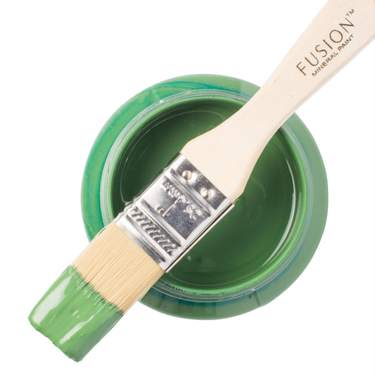 Paint brush dipped in green Park Bench Fusion Mineral Paint resting on top of an open paint jar