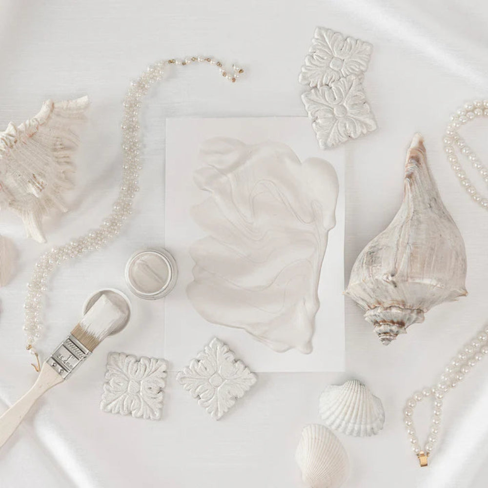 Collection of seashells and decorative items in Metallic Pearl colour on a light background