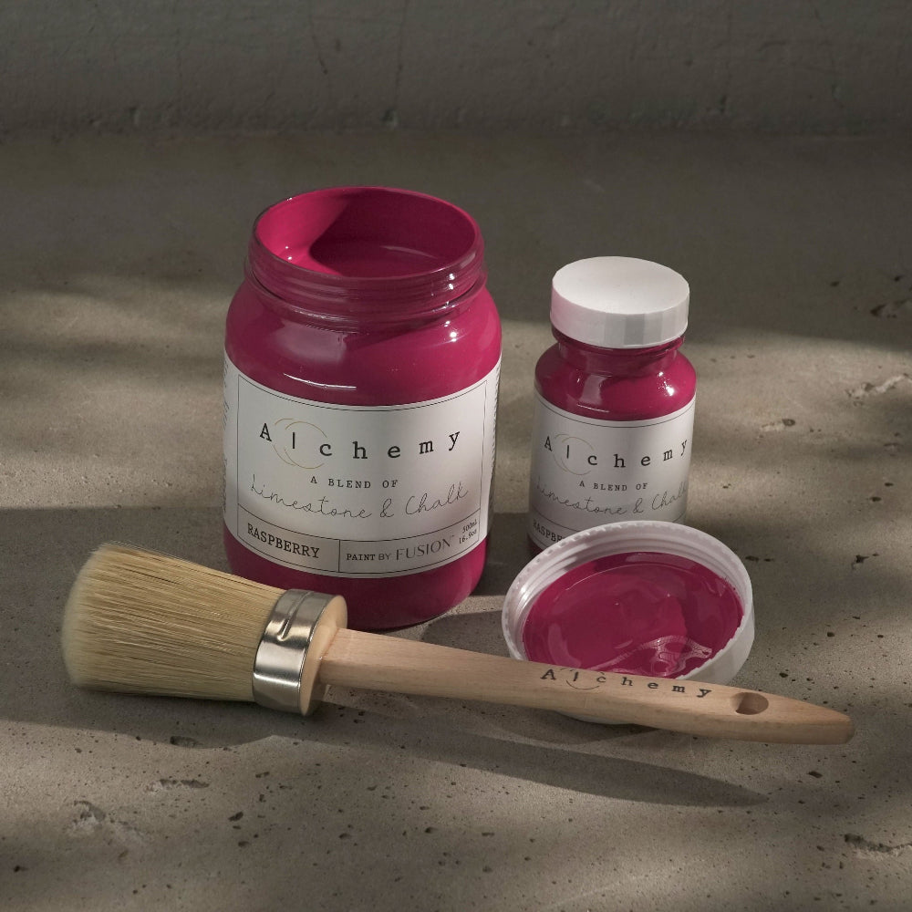 Jars of bright pink Raspberry paint from Alchemy by Fusion with a brush on a textured surface