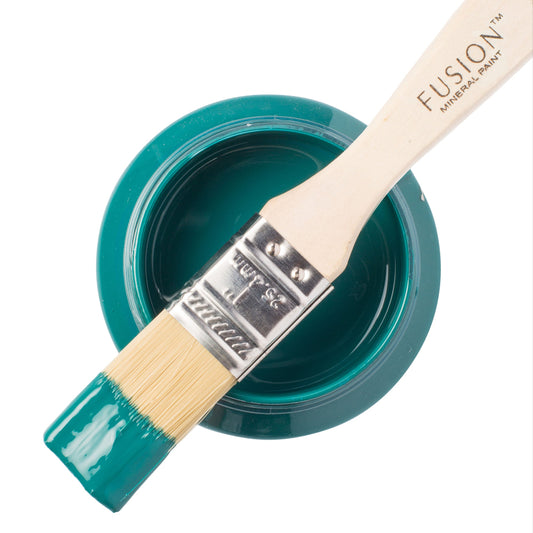 Paint brush dipped in Renfrew Blue Fusion Mineral Paint resting on an open paint container on a white background