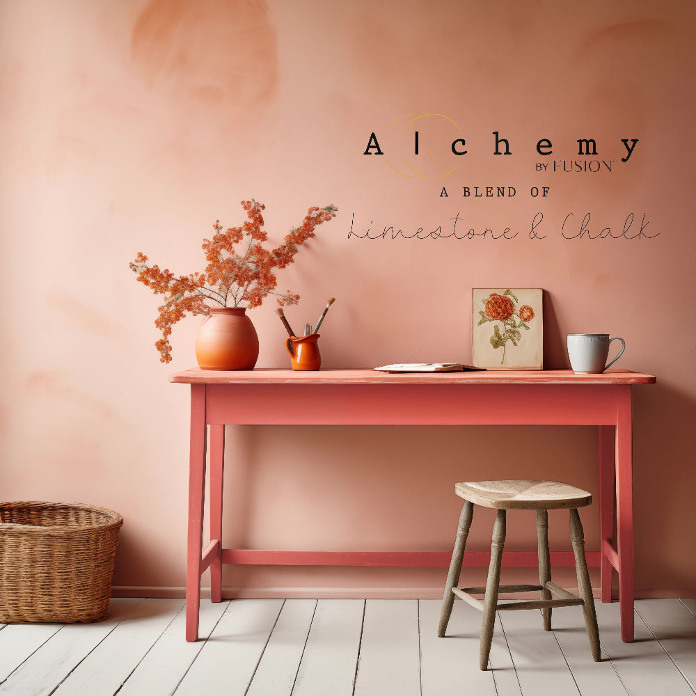 Wooden table painted in vibrant Sunset paint from Alchemy by Fusion with decor against a peach-coloured wall