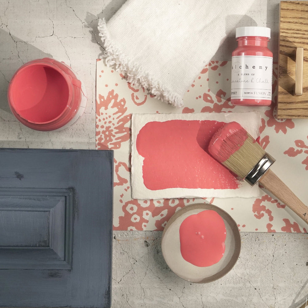 Samples of bright Sunset paint from Alchemy by Fusion and tools on a textured surface