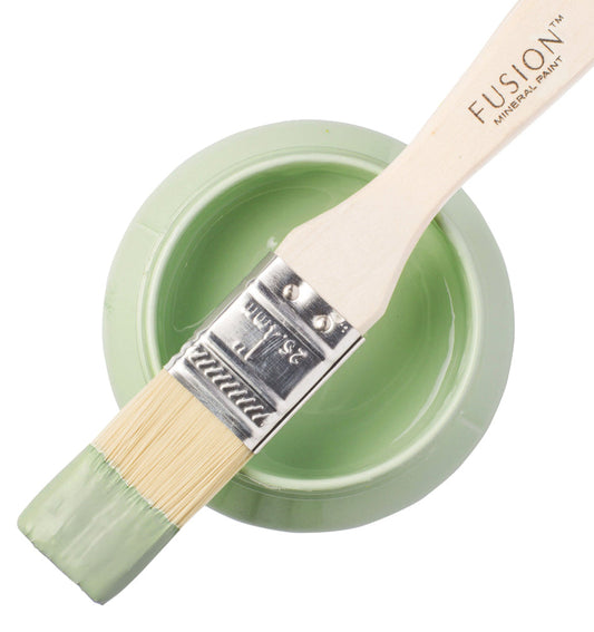 Paintbrush dipped in Upper Canada Green from Fusion Mineral Paint range balancing on top of a container of paint