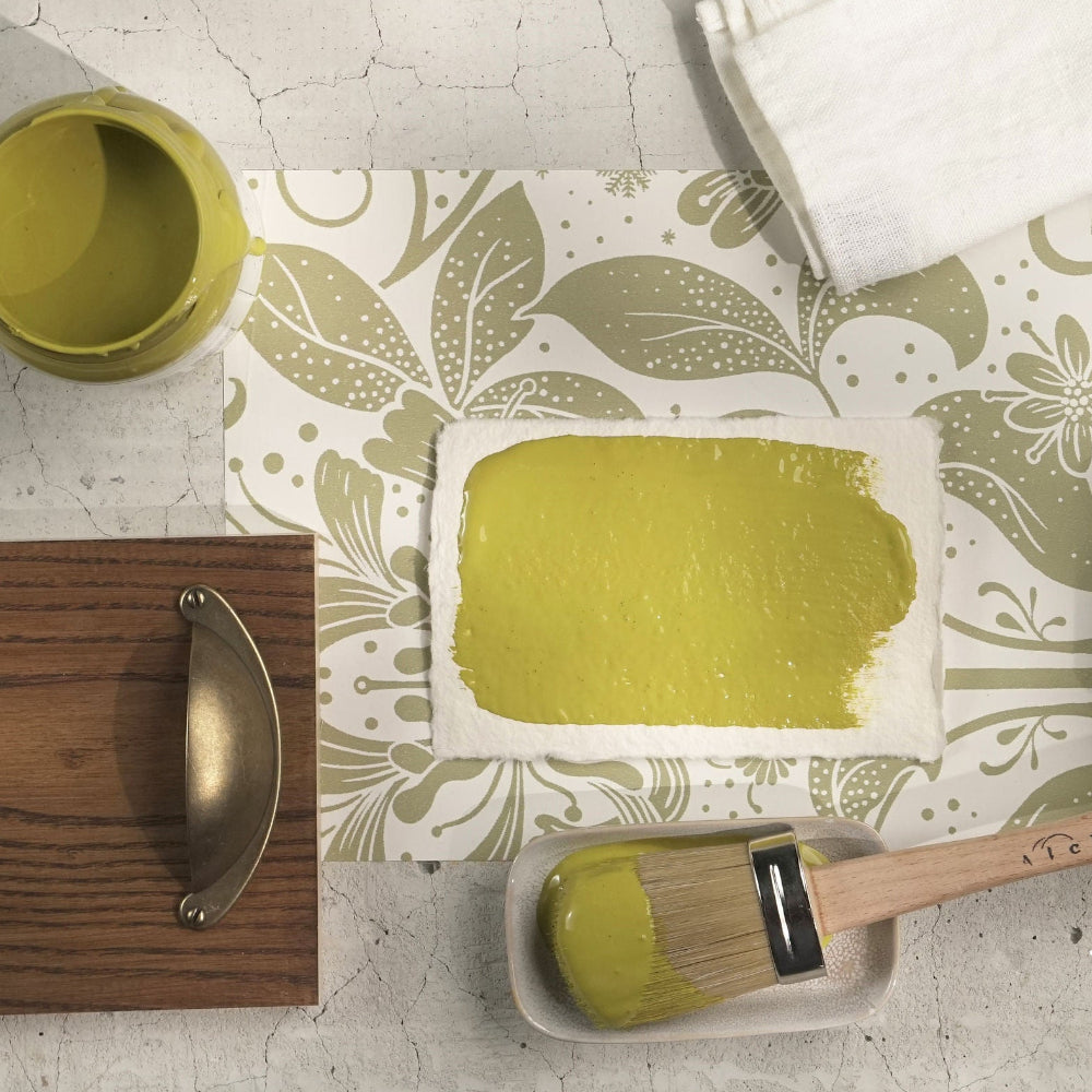 Decorative setting with samples of gorgeous green-mustard paint Willow from Alchemy by Fusion on a textured surface