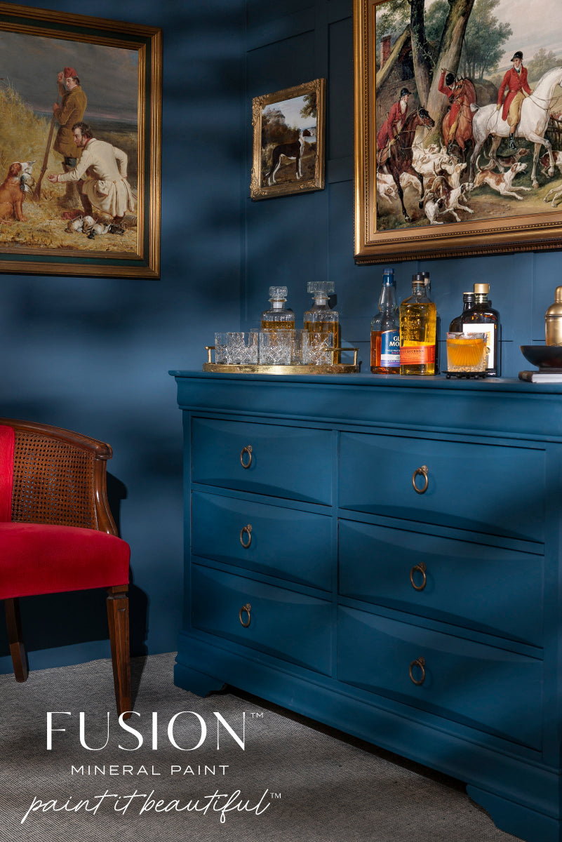 Dresser painted in blue Willowbank from the Fusion Mineral Paint range with bottles and glasses against a wall with framed paintings