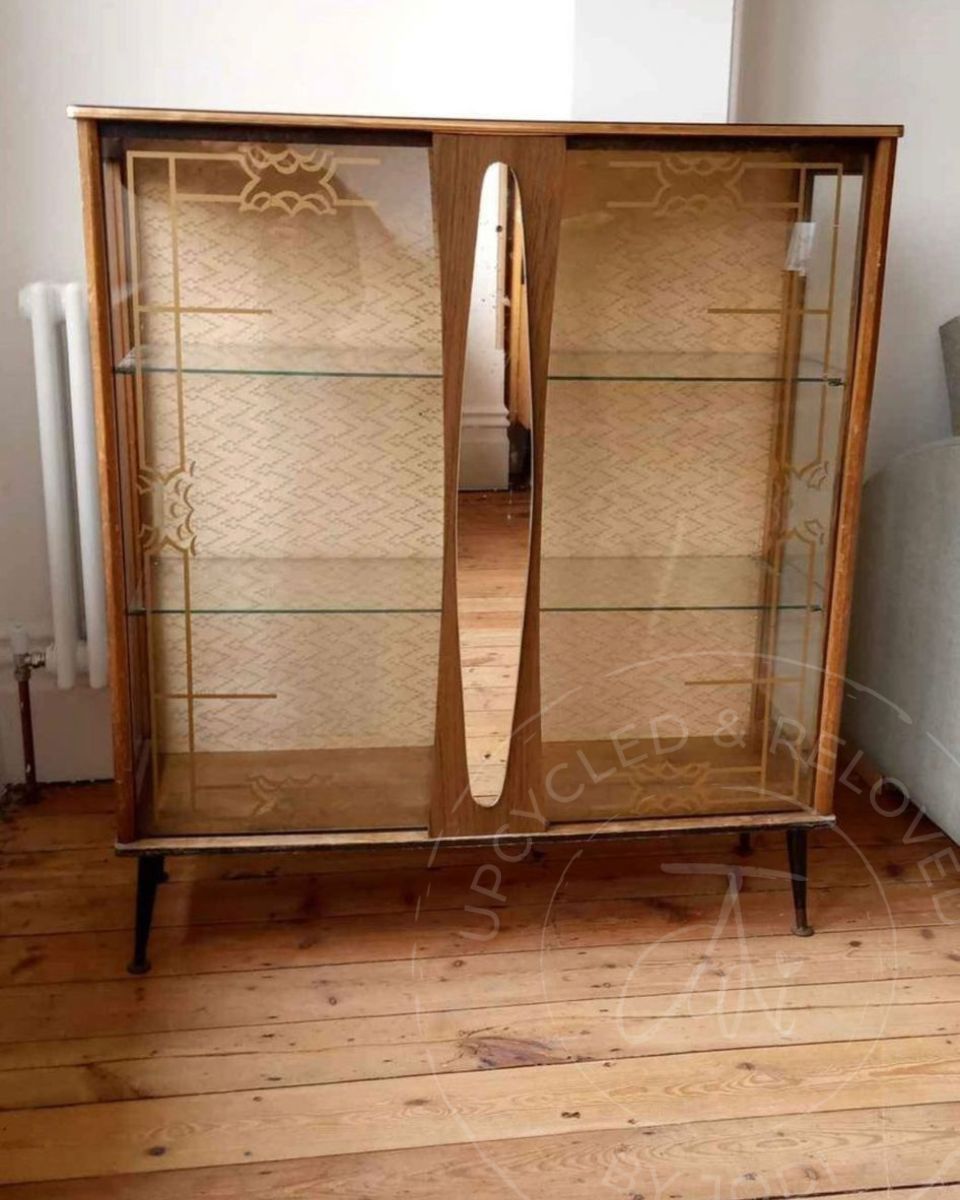 A vintage Art Deco glass display cabinet with gold door transfers before being transformed into a black and gold drinks cabinet by Upcycled & Reloved by Jodi in Surrey, UK.