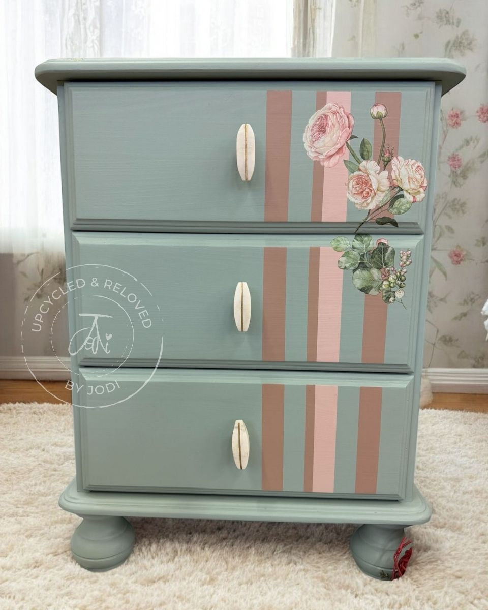 Upcycled pine bedside cabinet painted in duck egg blue, with floral design and striped pattern in pink hues. 