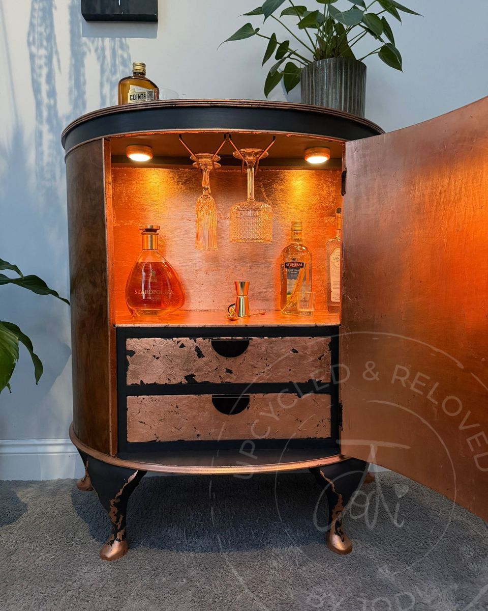 Upcycled bow fronted demi lune drinks cabinet, finished in charcoal Ash black and copper leaf, with LED lights illuminating the inside. 