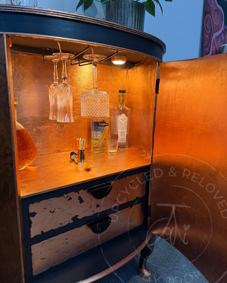 Upcycled bow fronted demi lune drinks cabinet, finished in charcoal Ash black and copper leaf, with LED lights illuminating the inside. 