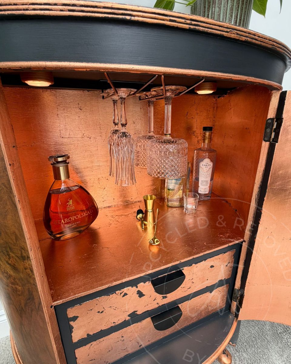 Upcycled bow fronted demi lune drinks cabinet, finished in charcoal Ash black and copper leaf, with LED lights illuminating the inside. 