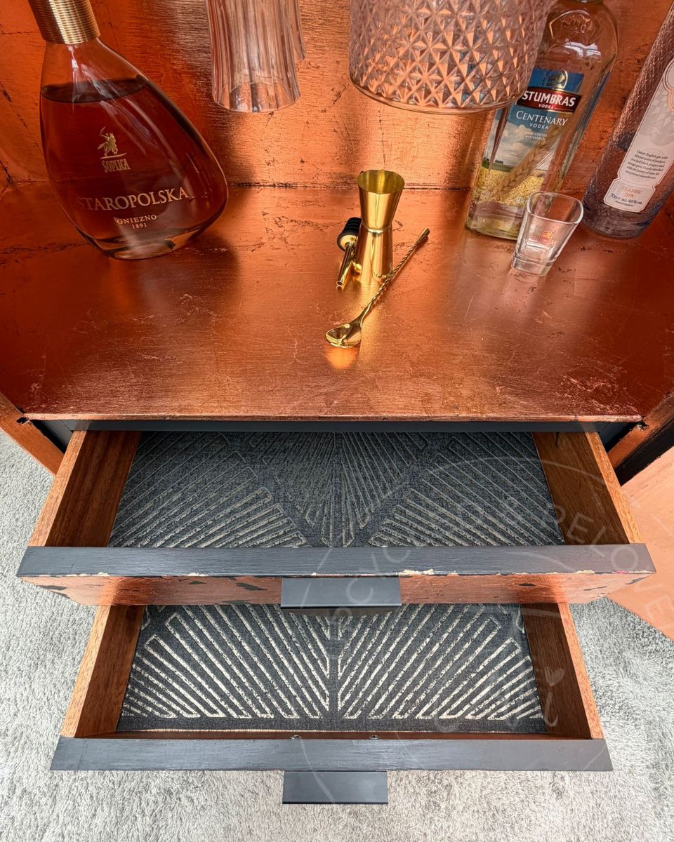 Open drawers with decoupage finish  on an upcycled black and copper demi lune drinks cabinet, also showing the copper inside with bottles and glasses.  