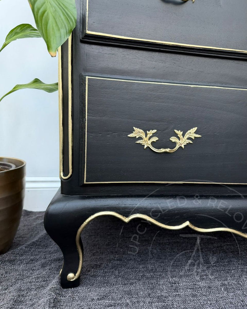 Close up of curved black chest of drawers leg and drawers with hand-painted gold detailing, transformed by Upcycled & Reloved by Jodi. 