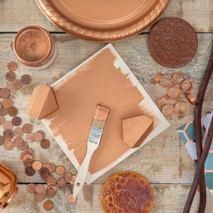Fusion Copper Metallic painted items including plates, coins, and a paintbrush on a wooden surface.