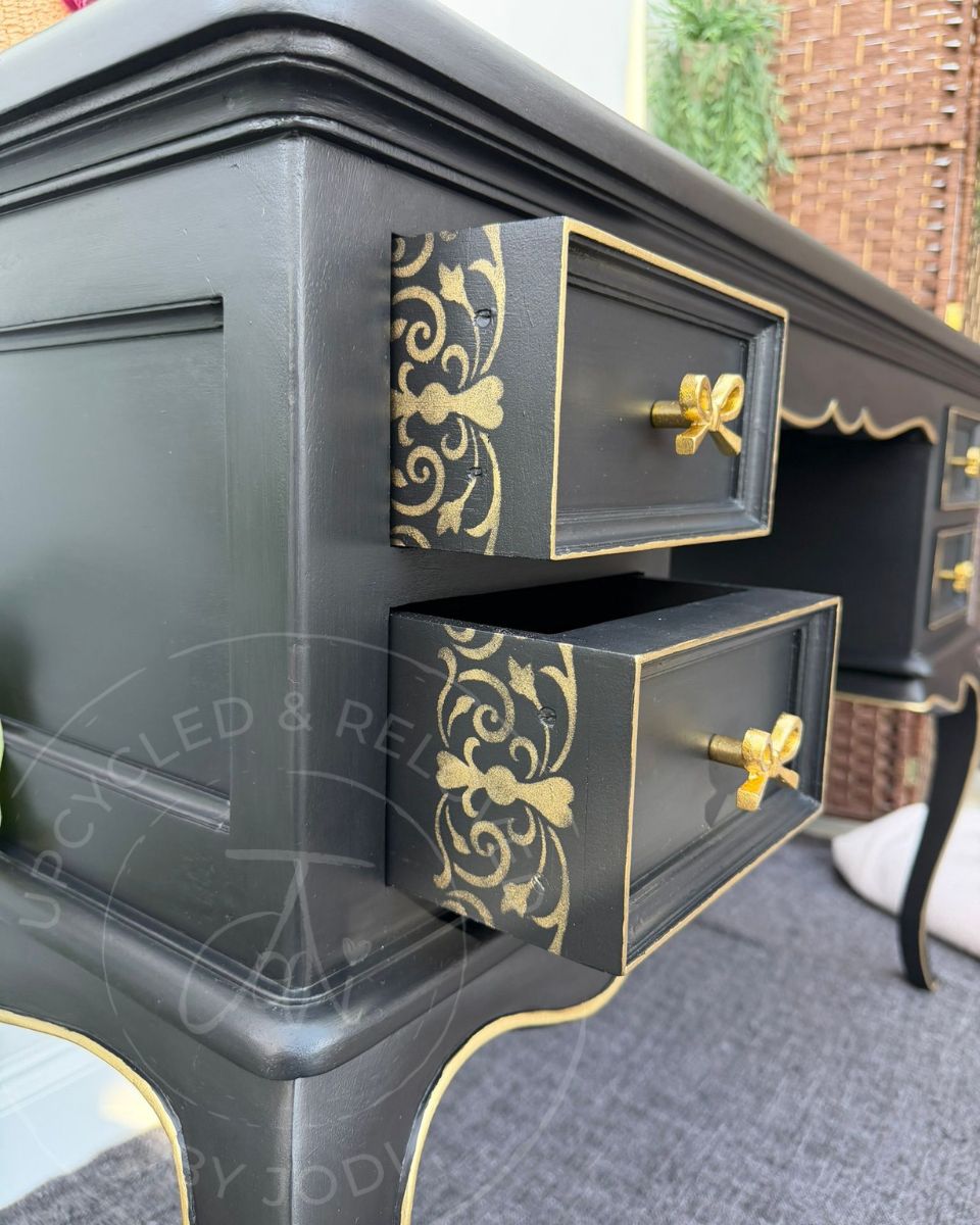 Black and gold dressing table with gold bow handles, decorative edging and stencilled drawer sides, refinished by Upcycled & Reloved by Jodi.