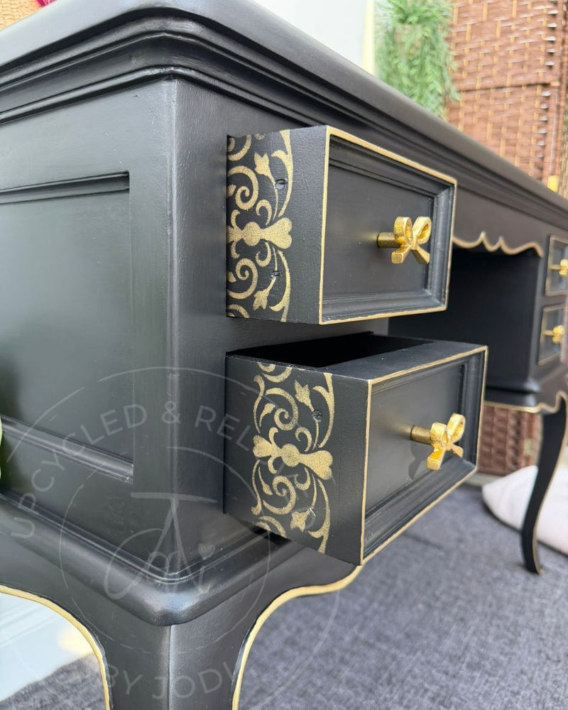 Black and gold dressing table with gold bow handles, decorative edging and stencilled drawer sides, refinished by Upcycled & Reloved by Jodi.