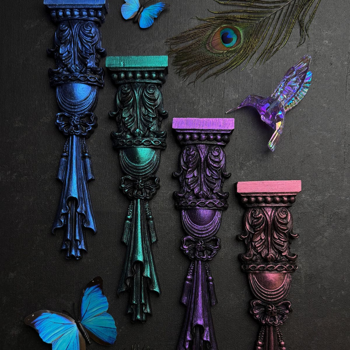 Decorative columns in various colours with butterflies and a peacock feather on a dark background, featuring Fusion Chromaflex Mineral Paint.