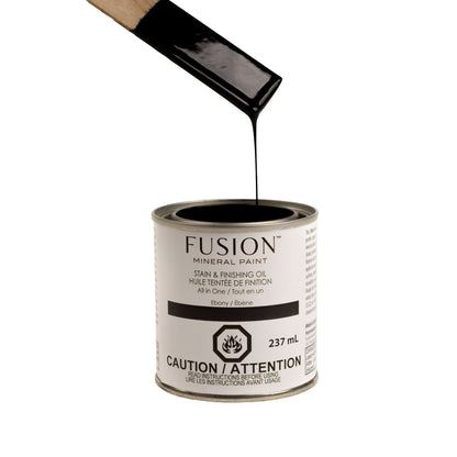 Fusion Stain and Finishing Oil in Ebony dripping off a wooden stirrer into a tin