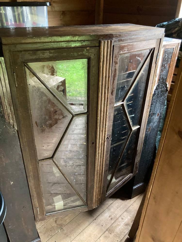 A bare wood gin cabinet with glass pane doors and no legs in a worn condition prior to being upcycled. 
