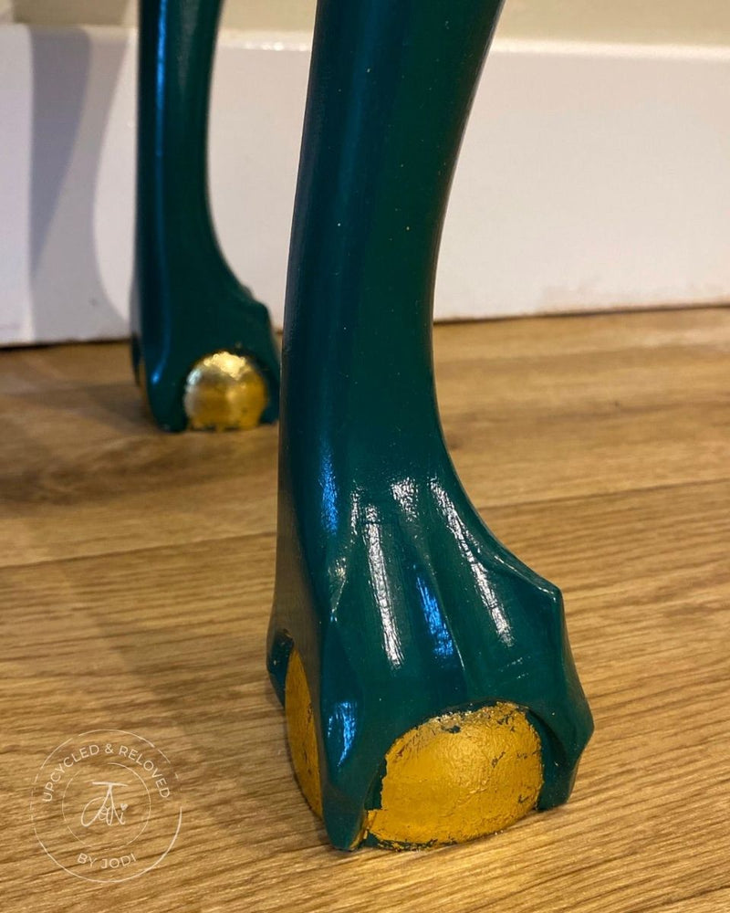 Close-up of a ball and claw foot of an upcycled gin cabinet, painted in green with gold detailing.