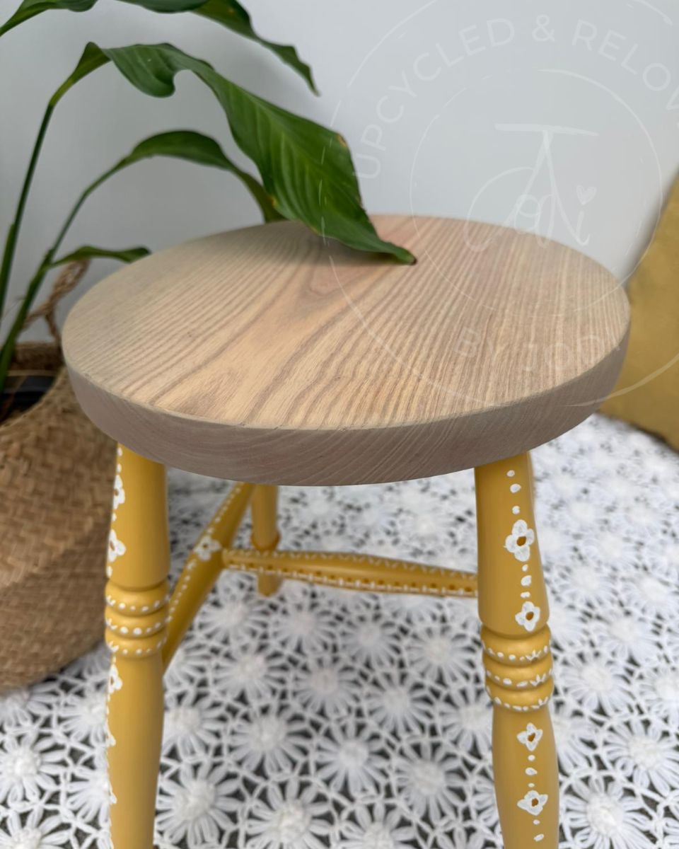 Upcycled stool with a raw pine top and legs painted in Fusion Mineral Paint in Prairie Sunset, a mustard yellow, finished with hand-painted folk-inspired decorative patterns in white. 