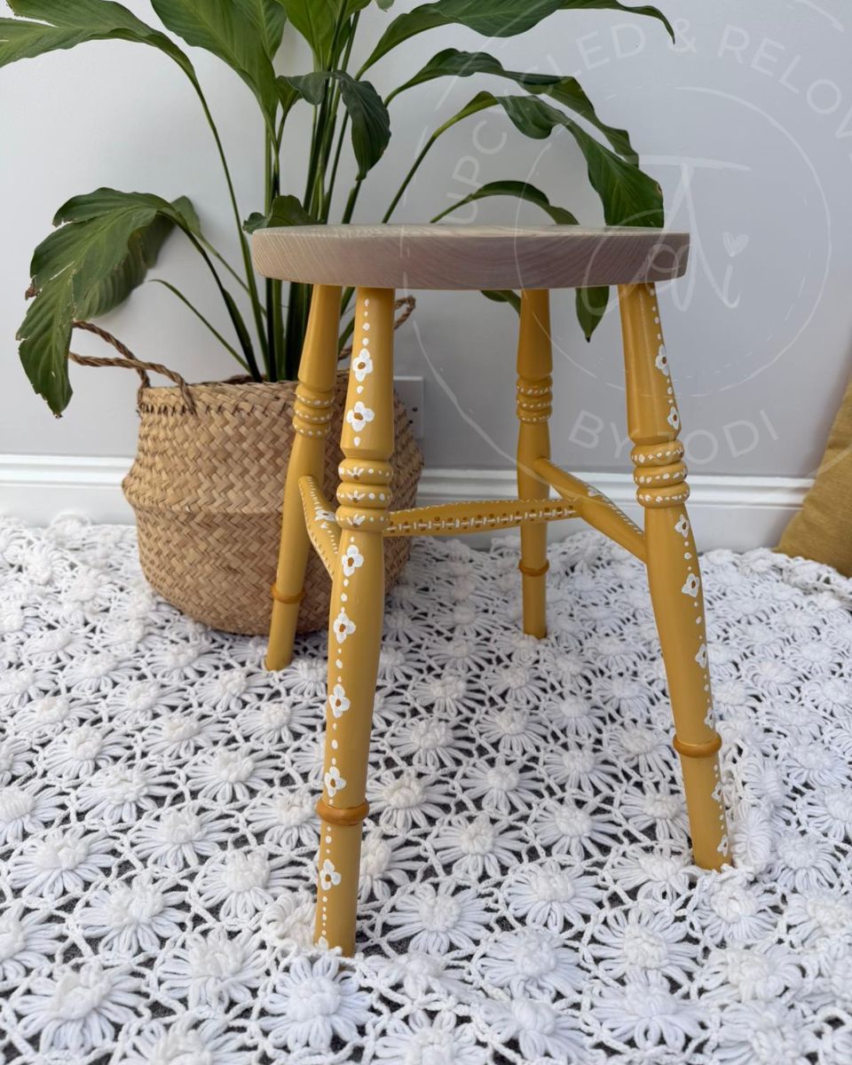 Upcycled stool with a raw pine top and legs painted in Fusion Mineral Paint in Prairie Sunset, a mustard yellow, finished with hand-painted folk-inspired decorative patterns in white. 