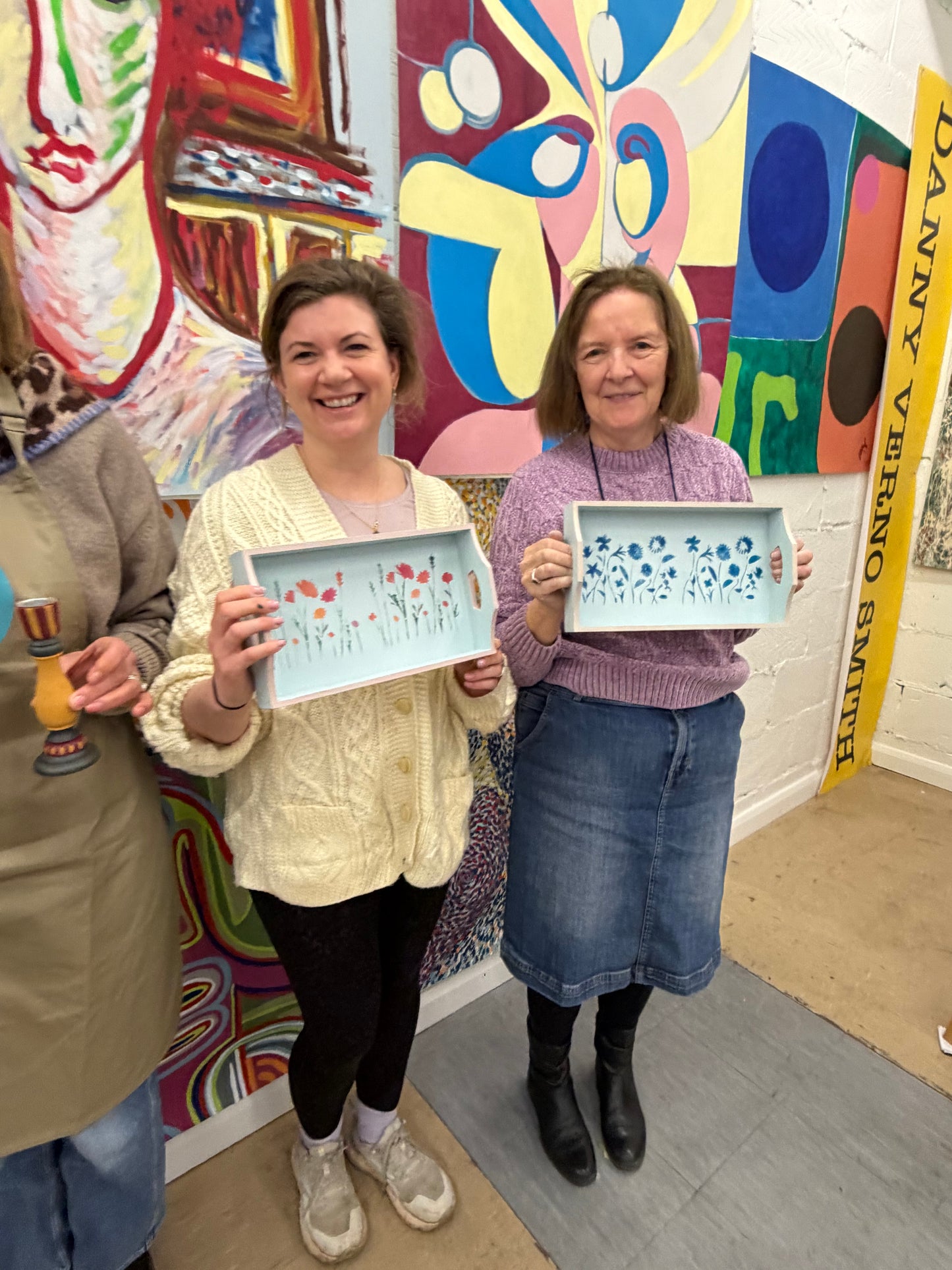 Attendees of paint and Prosecco workshop displaying the wooden trays painted at a creative evening in Surrey. Creative workshop delegates proudly displaying their painted home decor after enjoying a painting evening in Leatherhead
