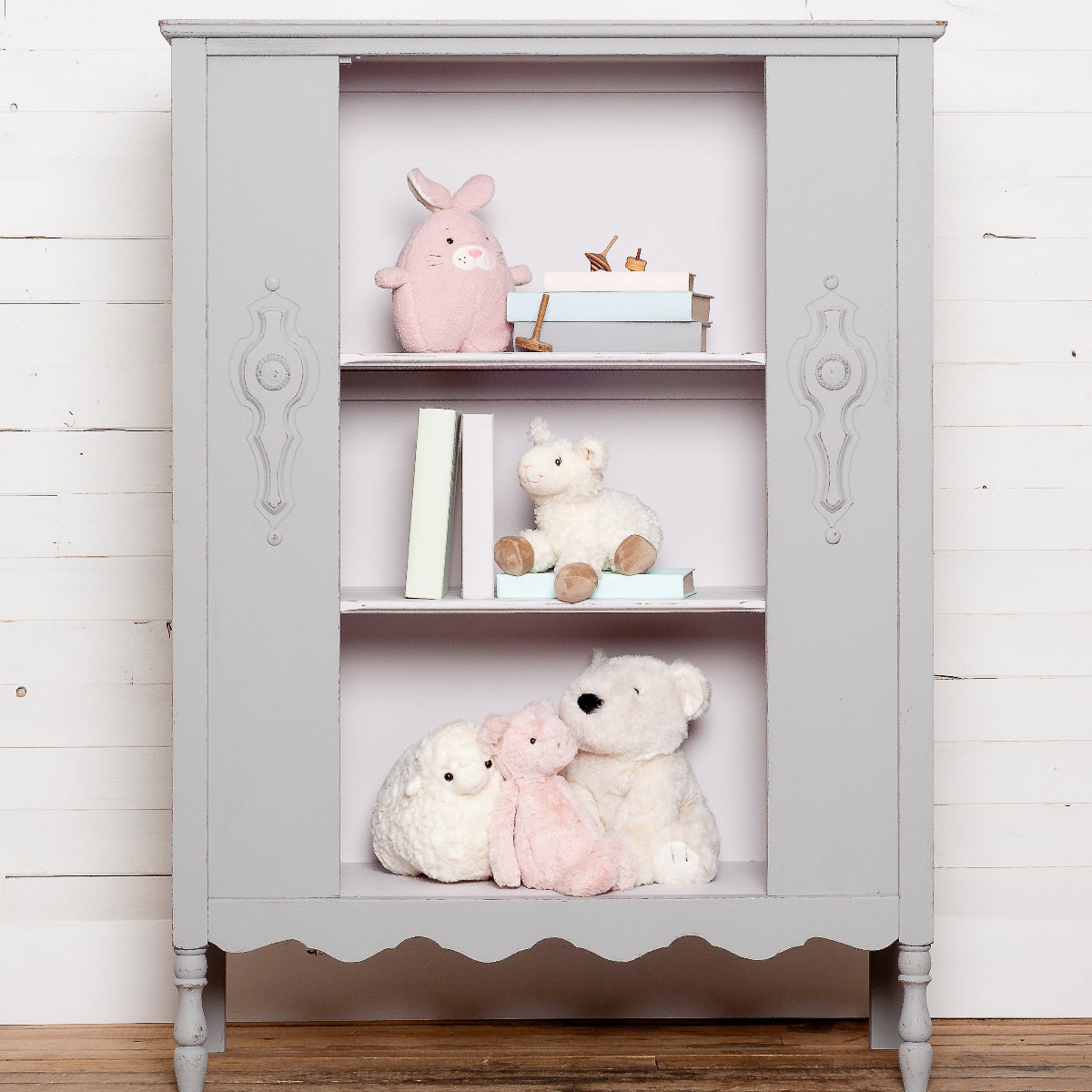 Bookshelf painted in wooly grey Little Lamb from Fusion Mineral Paint with stuffed animals against a white wooden wall,