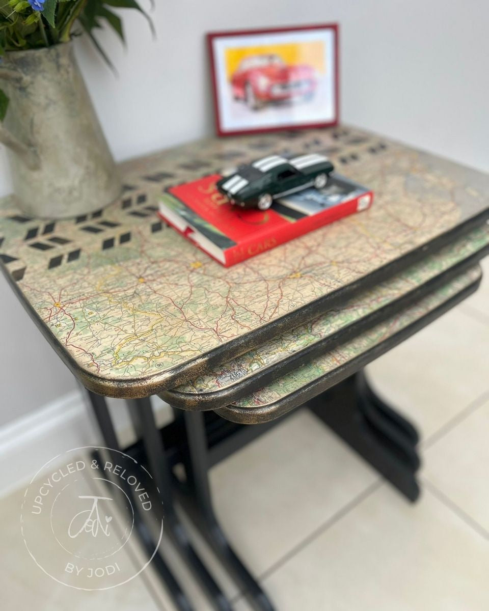 Set of three upcycled nesting tables in Fusion ash black with a map decoupage on the tops and stencilled track pattern across the top. Gold edging around the nest of tables 