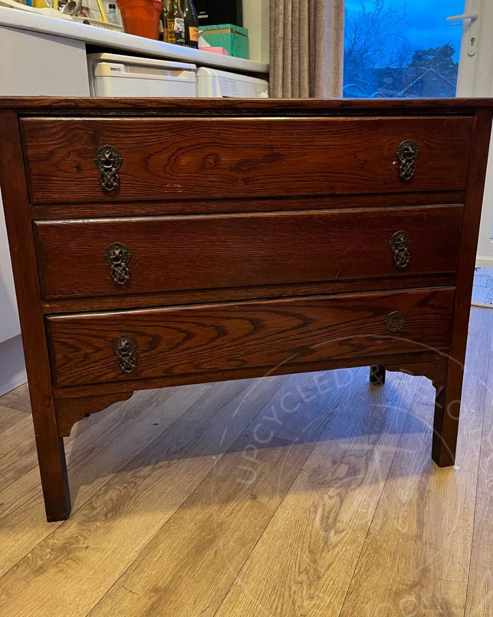Wooden chest of drawers with brass handles positioned in a kitchen, ready to be Upcycled & Reloved by Jodi.