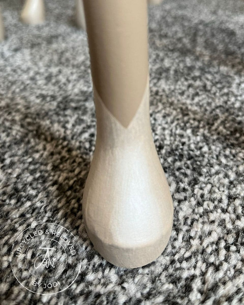 Close-up view of the leg from a set of nesting tables that have been upcycled and painted in neutrals with V-shaped detail on the feet